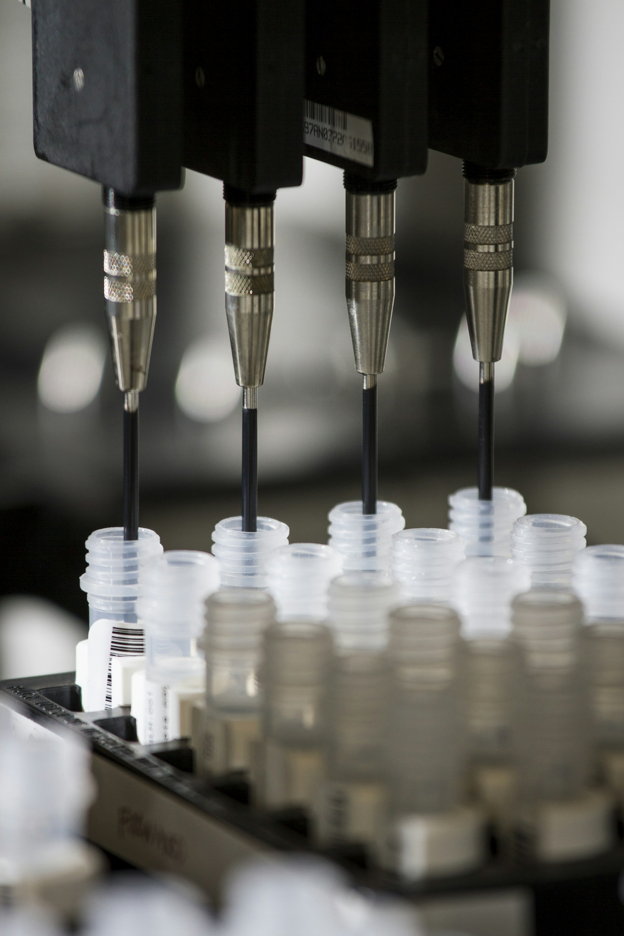 An automated liquid-handling robot pipetting barcoded DNA sample tubes in a genomics laboratory
